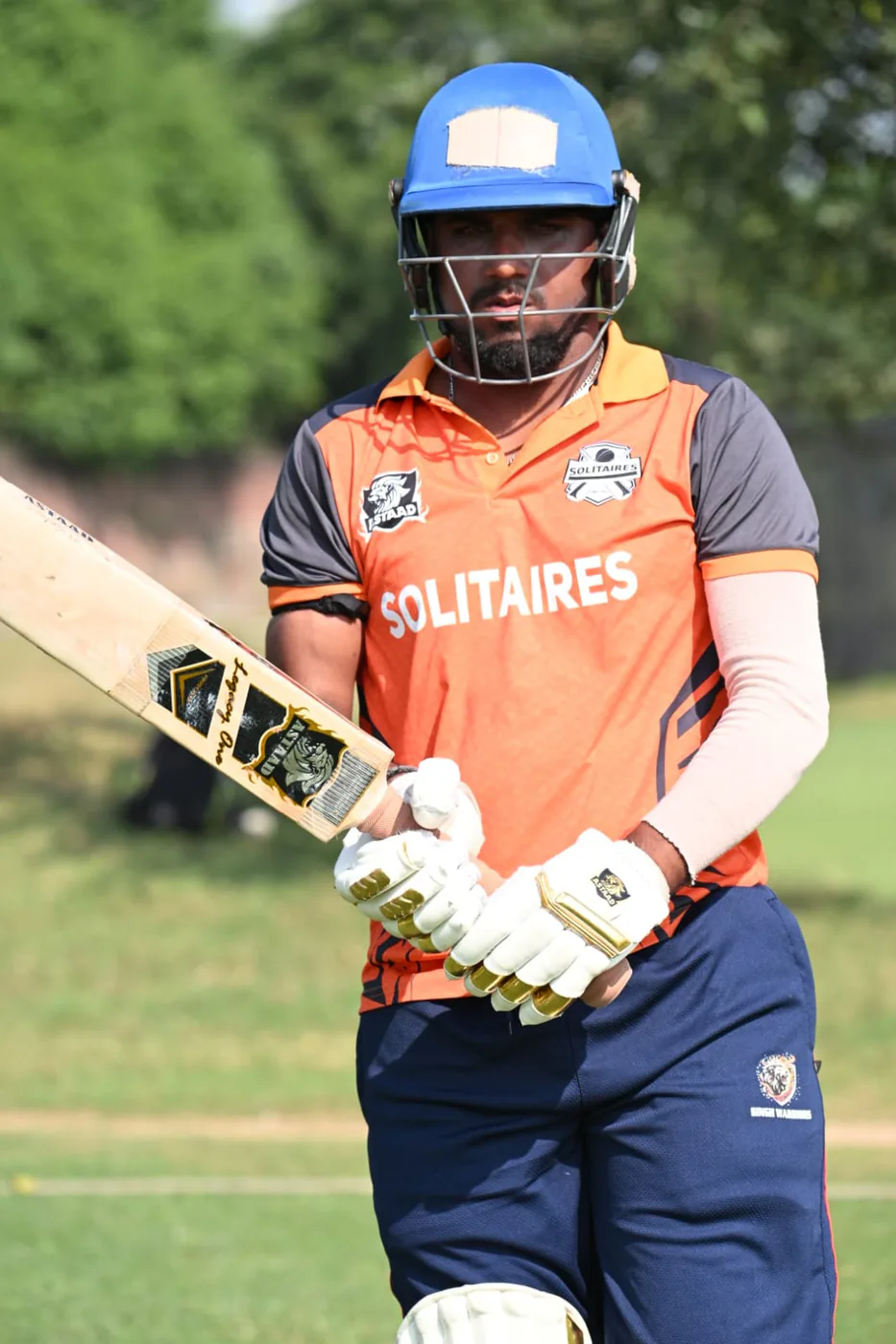 A batter in a helmet walking out with an Astaad bat