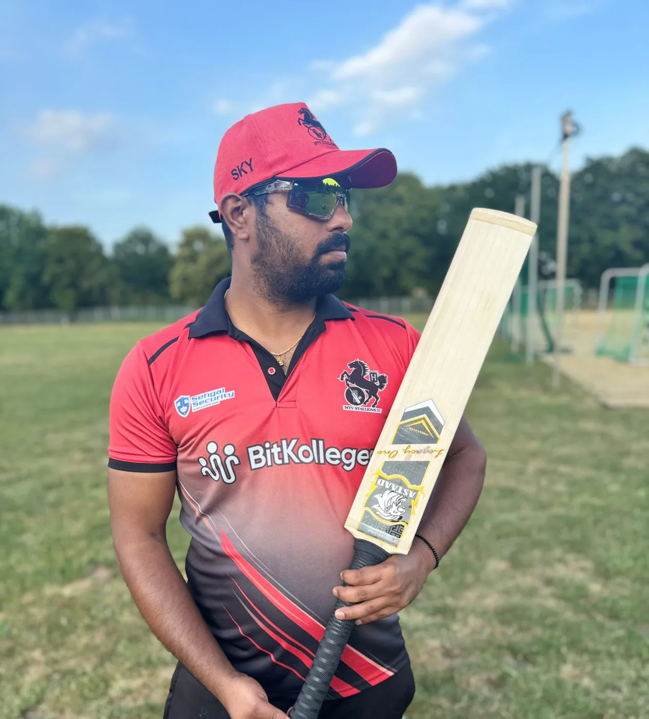 A player in a red cap holding an Astaad bat
