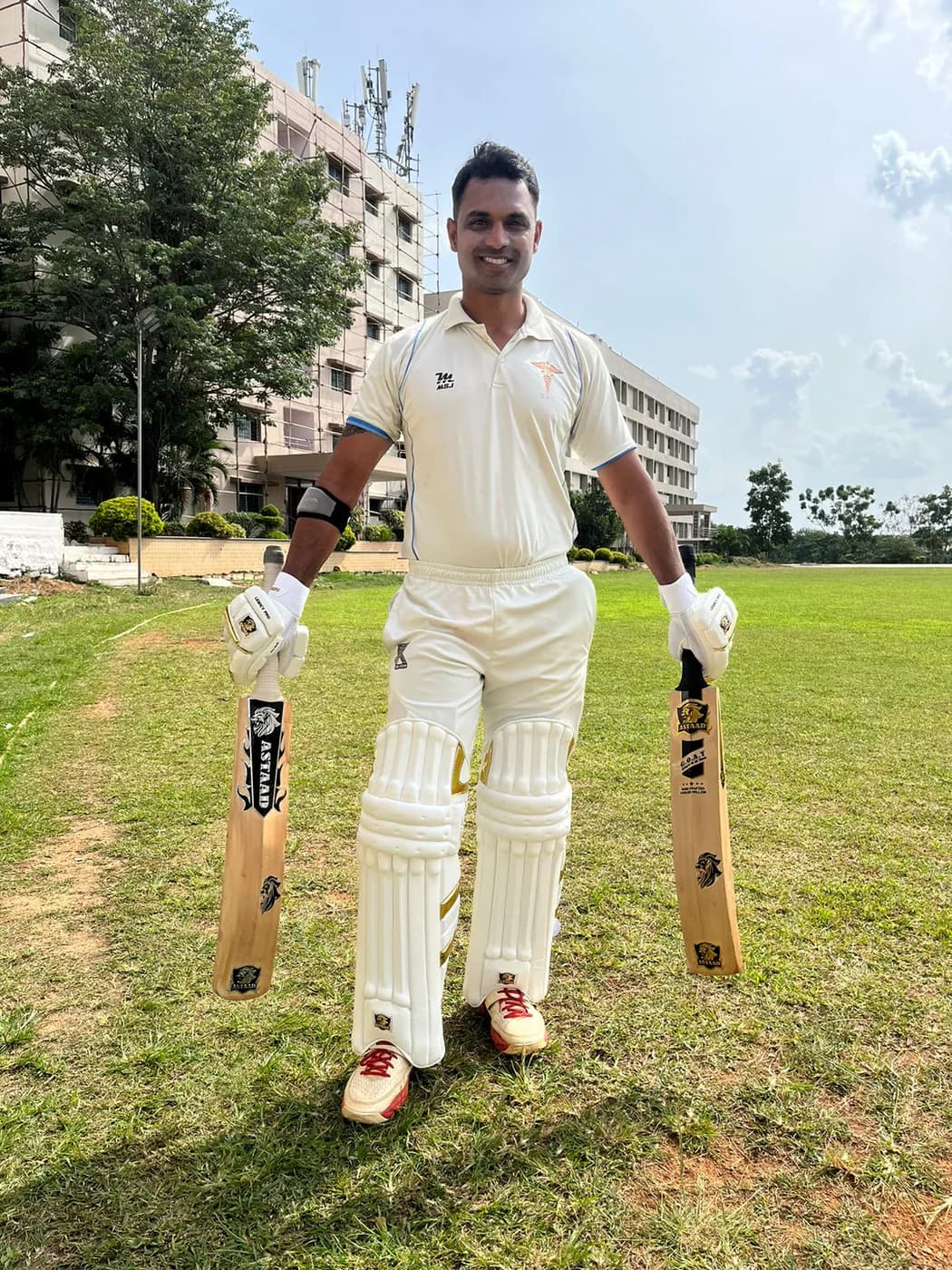 A batter in whites holding two Astaad bats